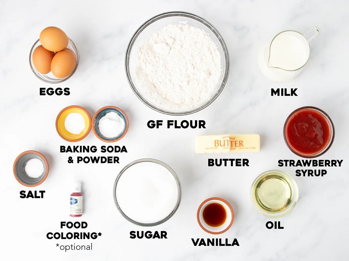 Overhead view of measured and labeled ingredients for gluten free strawberry cake on a white surface