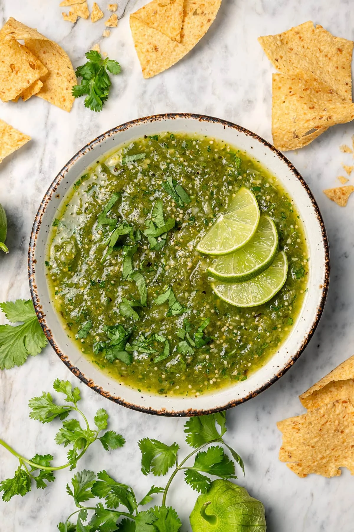 Overhead view of salsa verde in bowl with 3 lime slices