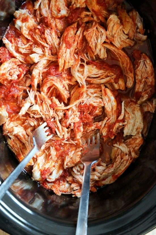 Overhead view of shredded spicy harissa chicken inside the slow cooker.