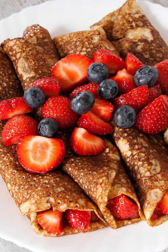 Overhead view of Swedish pancakes with fruit on top of them 