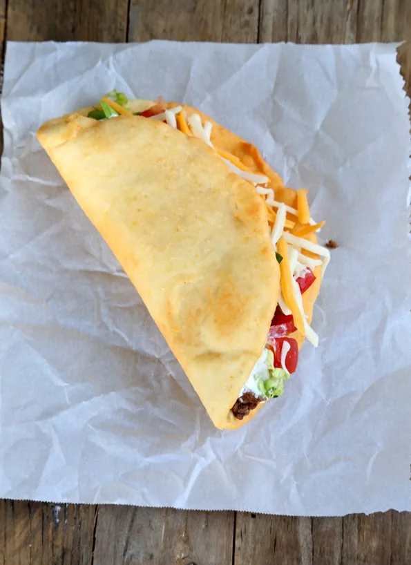 Overhead view of taco on white surface.