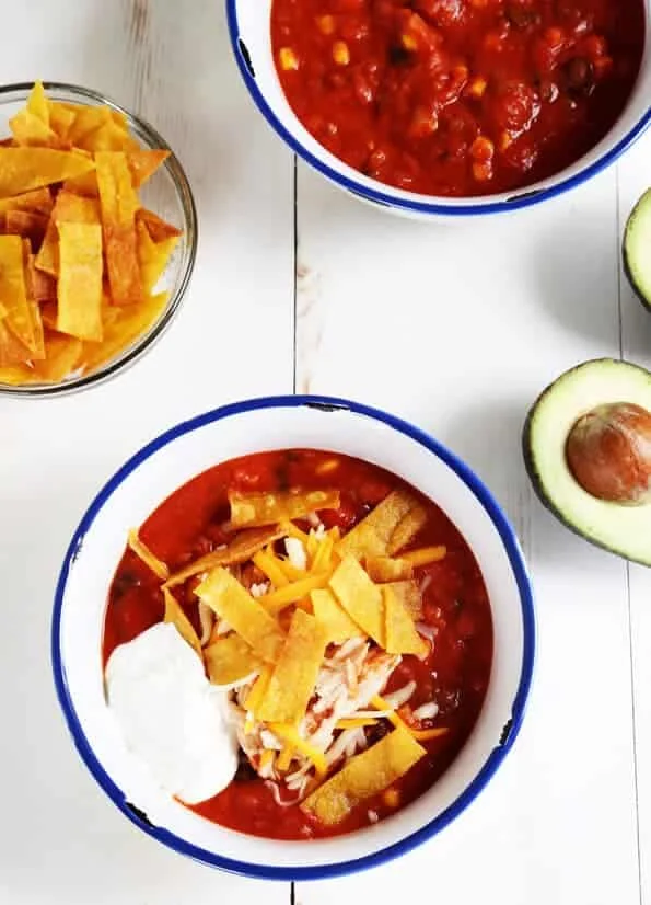 Overhead view of taco soup on white surface with avocados.