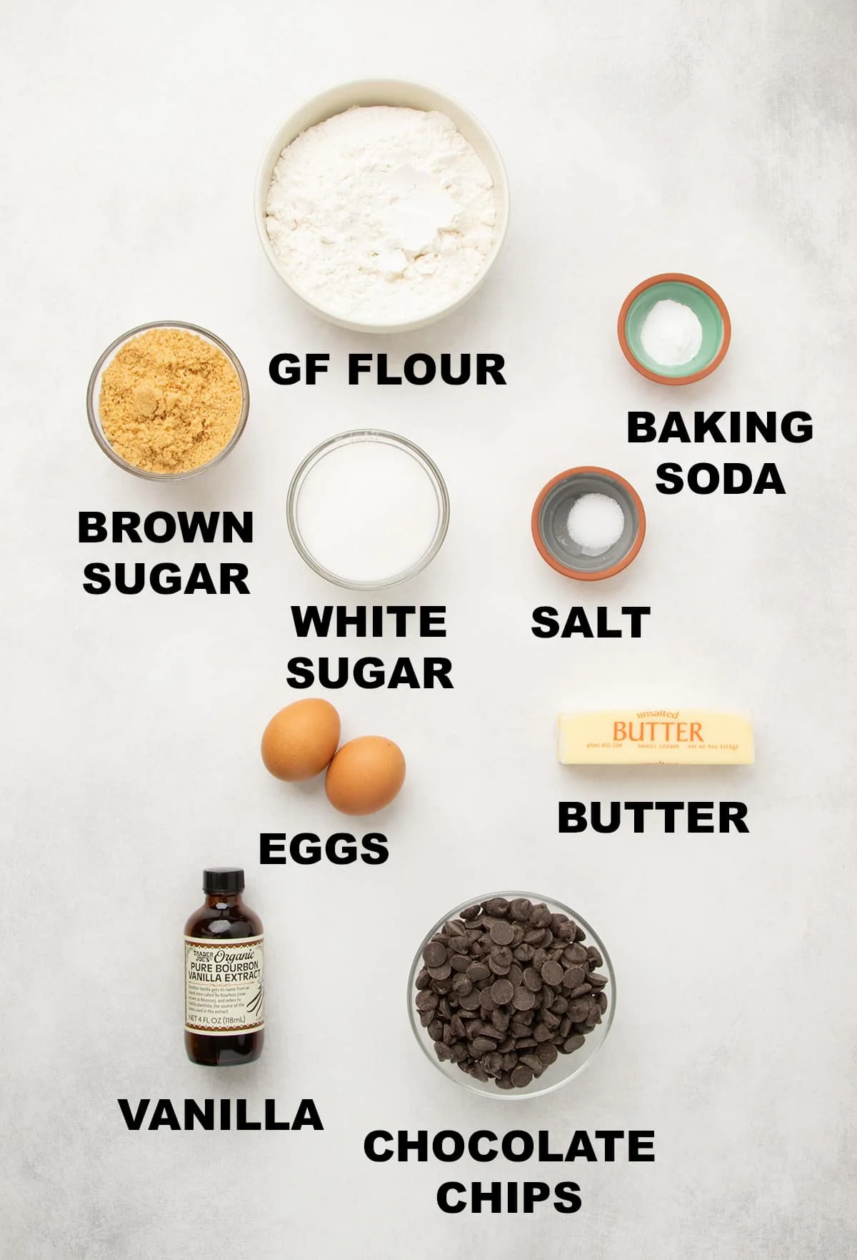 Overhead view of the ingredients in round bowls with words printed below each ingredient on light marble surface.