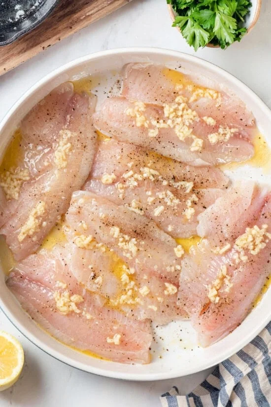 Overhead view of tilapia fillets in pan before baking