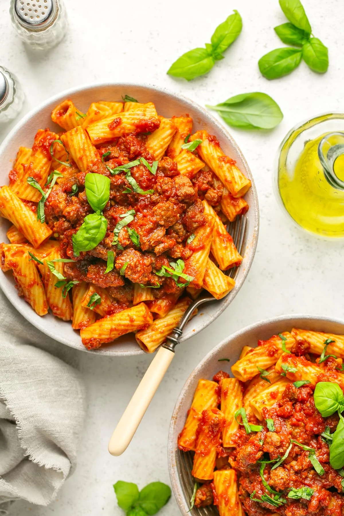 Overhead view of two bowls with sausage pasta sauce served over rigatoni.