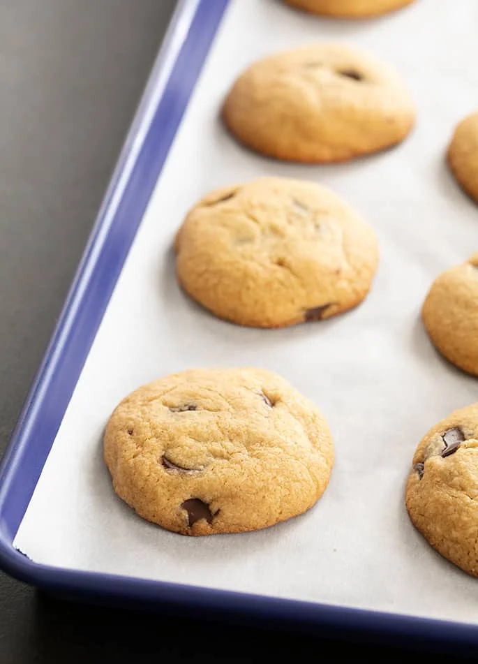 Peanut butter chocolate chip cookies on white paper on a blue tray