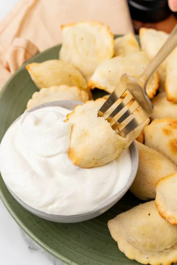 pierogi being dipped into sour cream