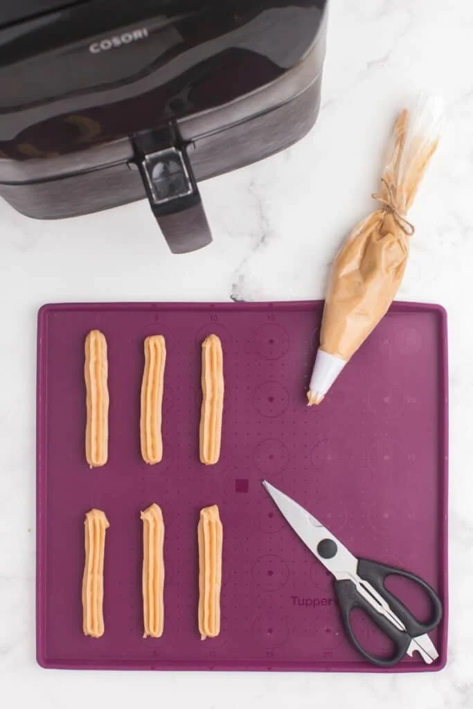 piping churros onto a silicone mat 