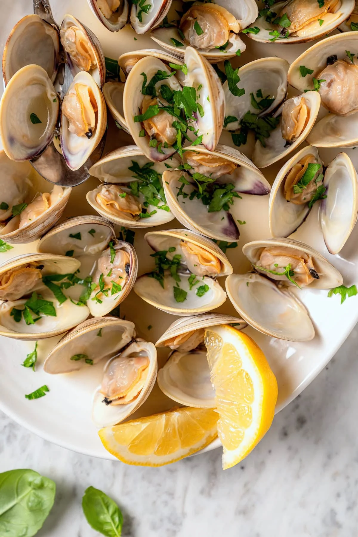 Platter of steamed clams with lemon wedges.