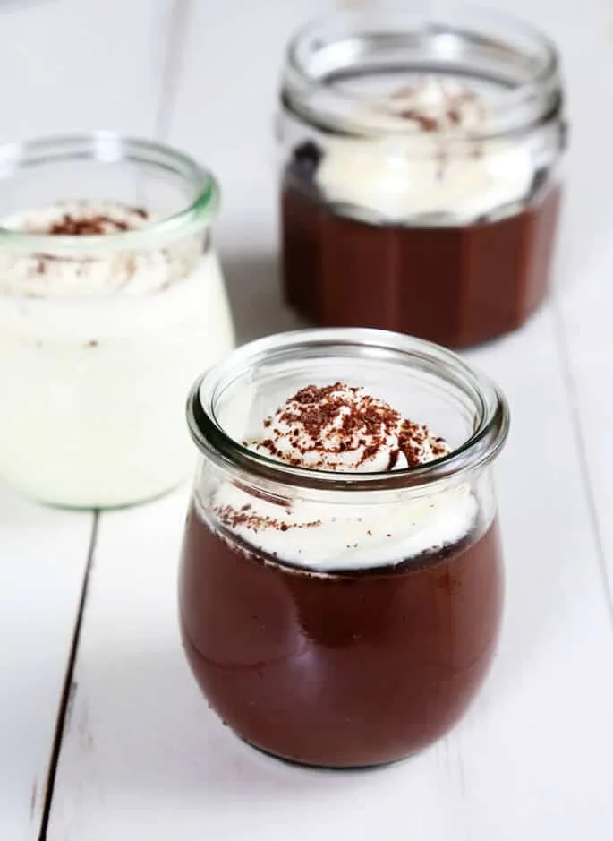 Pudding with whip cream in a jar on white surface 