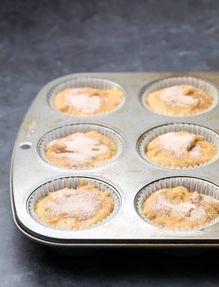Raw applesauce muffin batter with cinnamon sugar in muffin wells