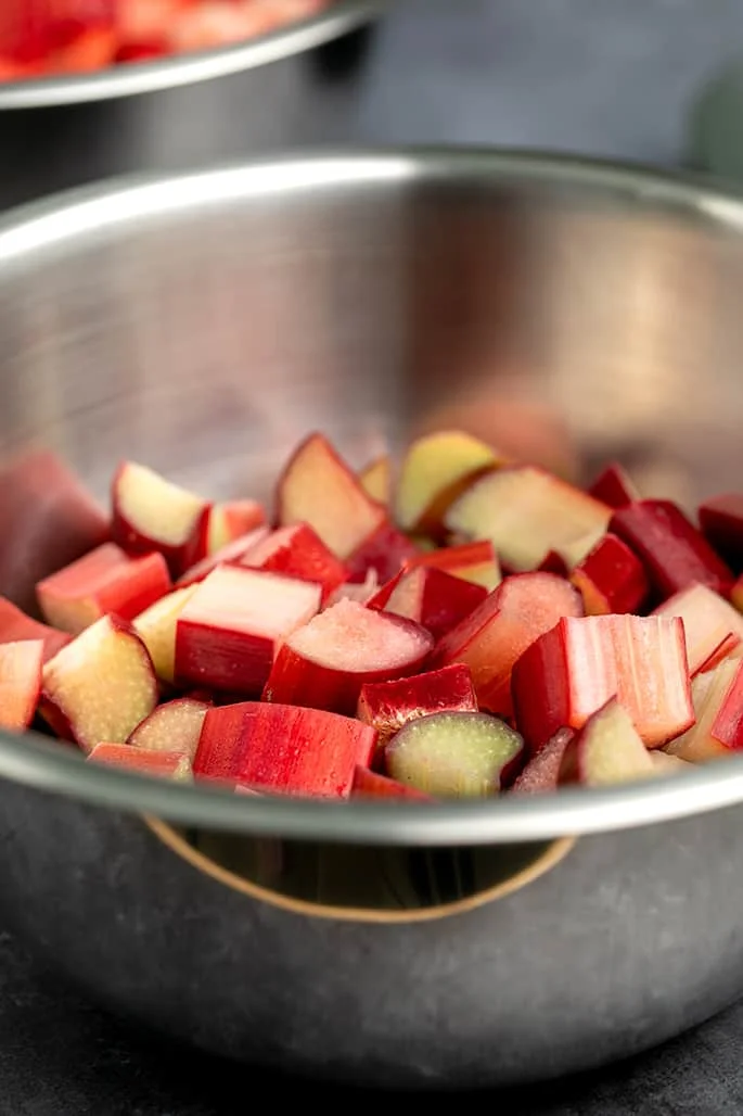 Raw chopped rhubarb stalks in metal mixing bowl