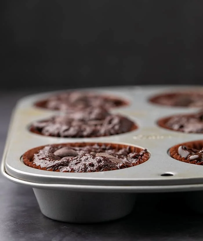 Raw gluten free chocolate muffin batter in 6-cup metal muffin tin