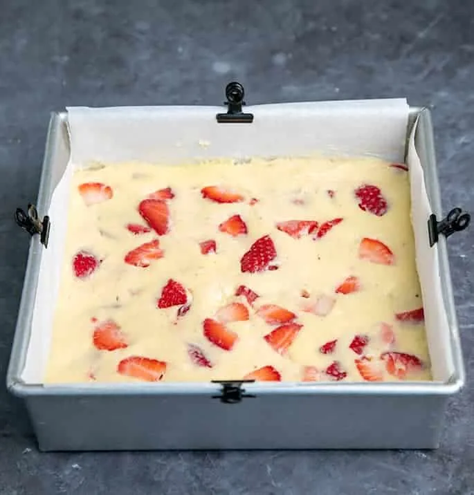 Raw strawberry breakfast cake batter in square baking pan