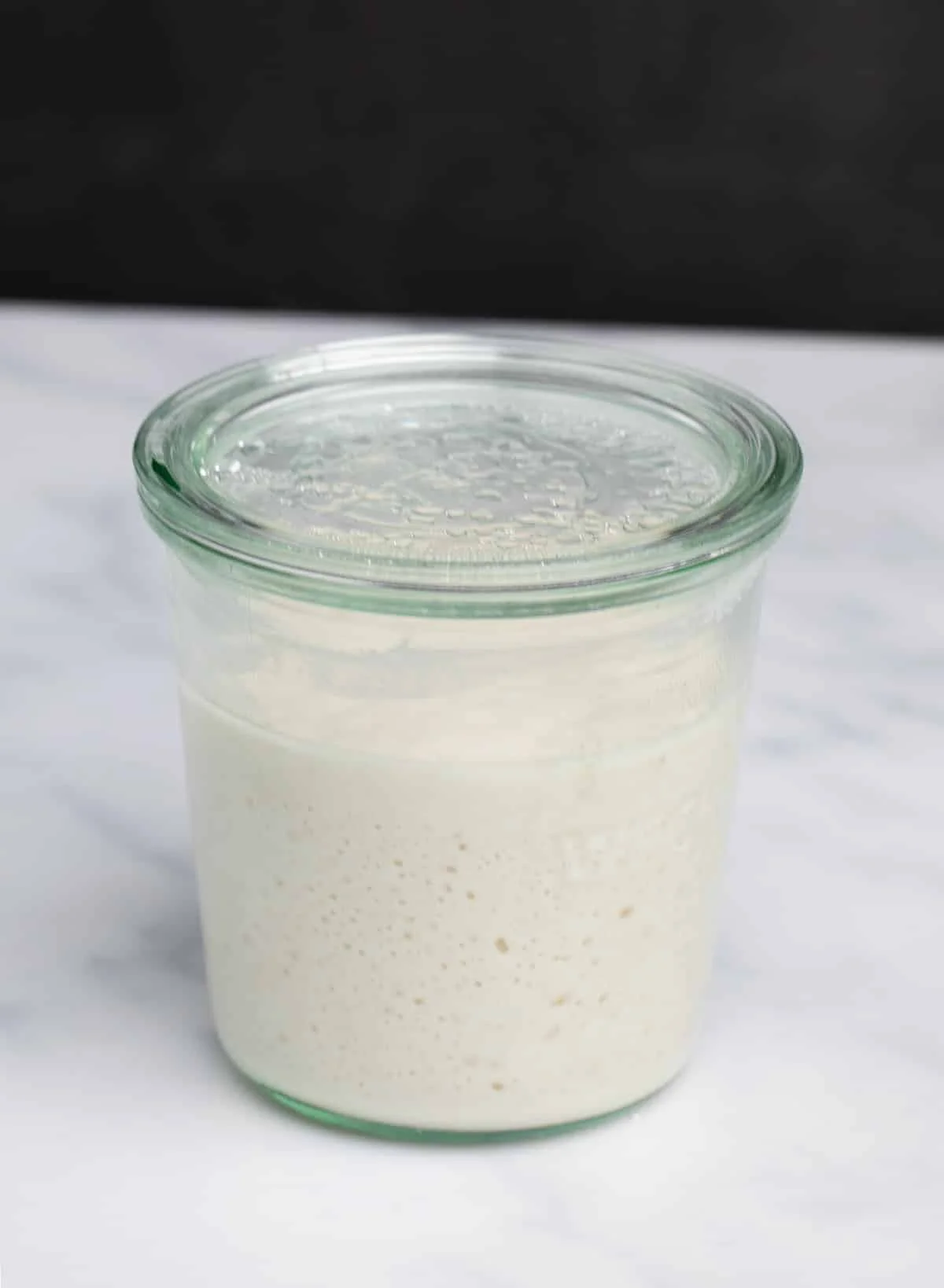 Risen gluten free sourdough starter in glass jar with glass lid