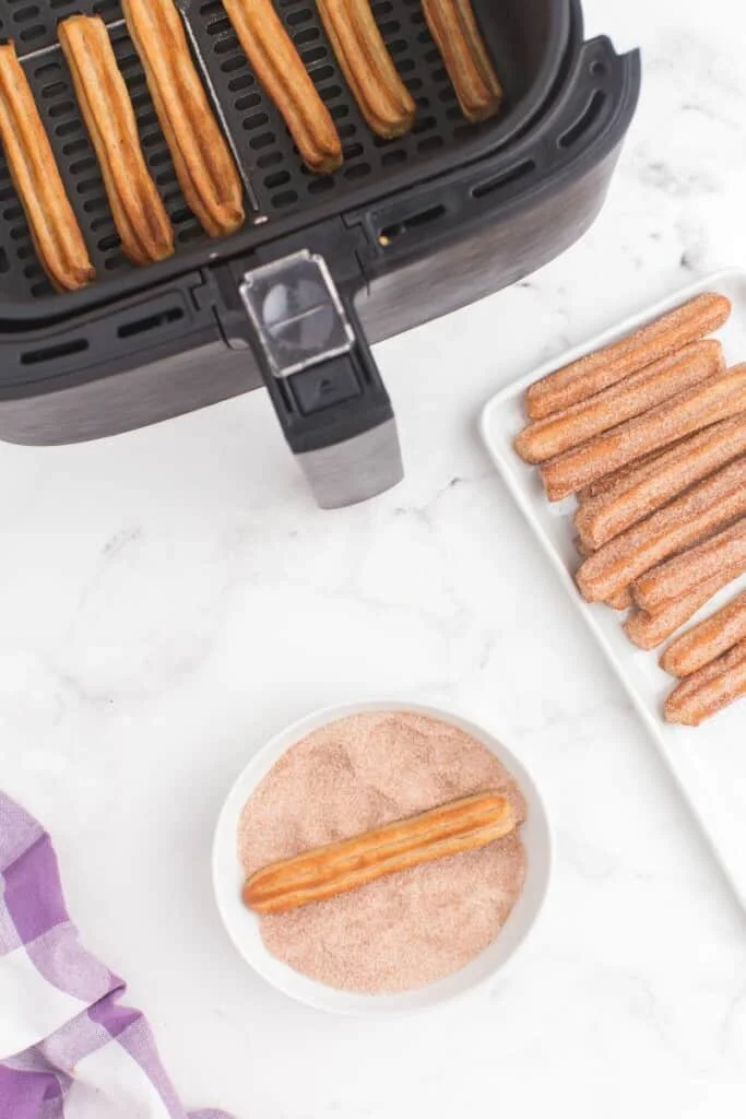 rolling churros in cinnamon sugar 