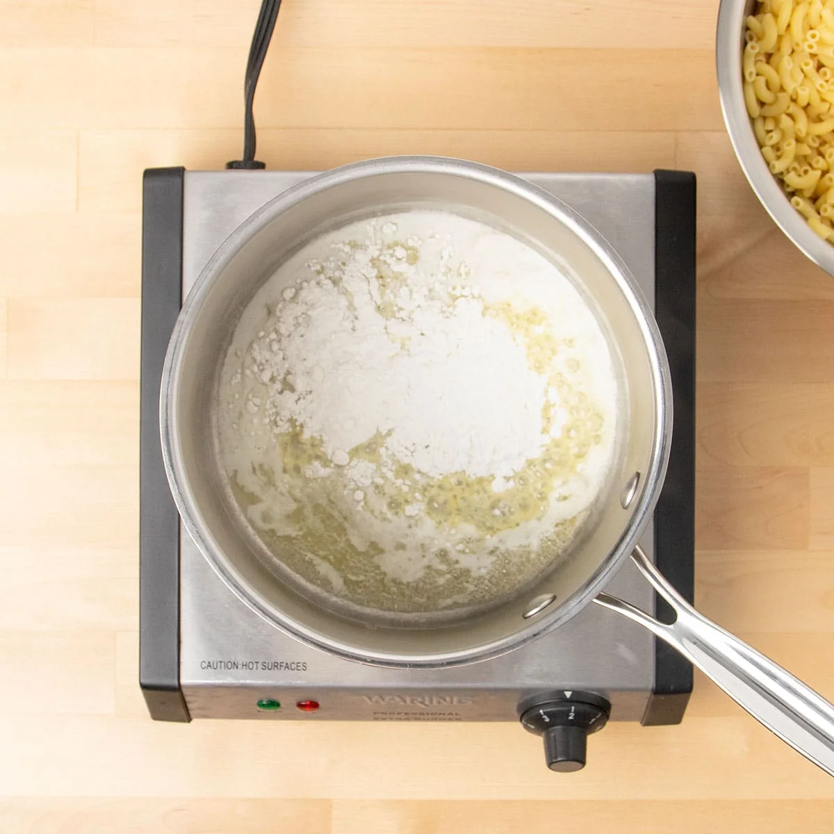 Round metal saucepan with melted butter and unmixed white flour.