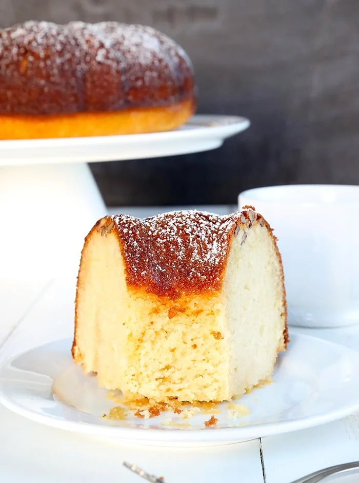 Rum cake slice from bundt cake on white plate with piece taken