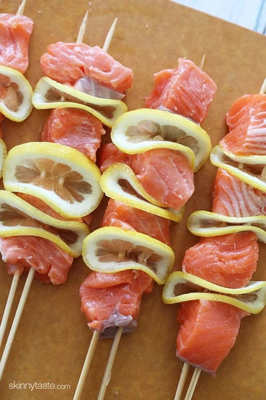 Salmon threaded onto skewers with lemon slices.