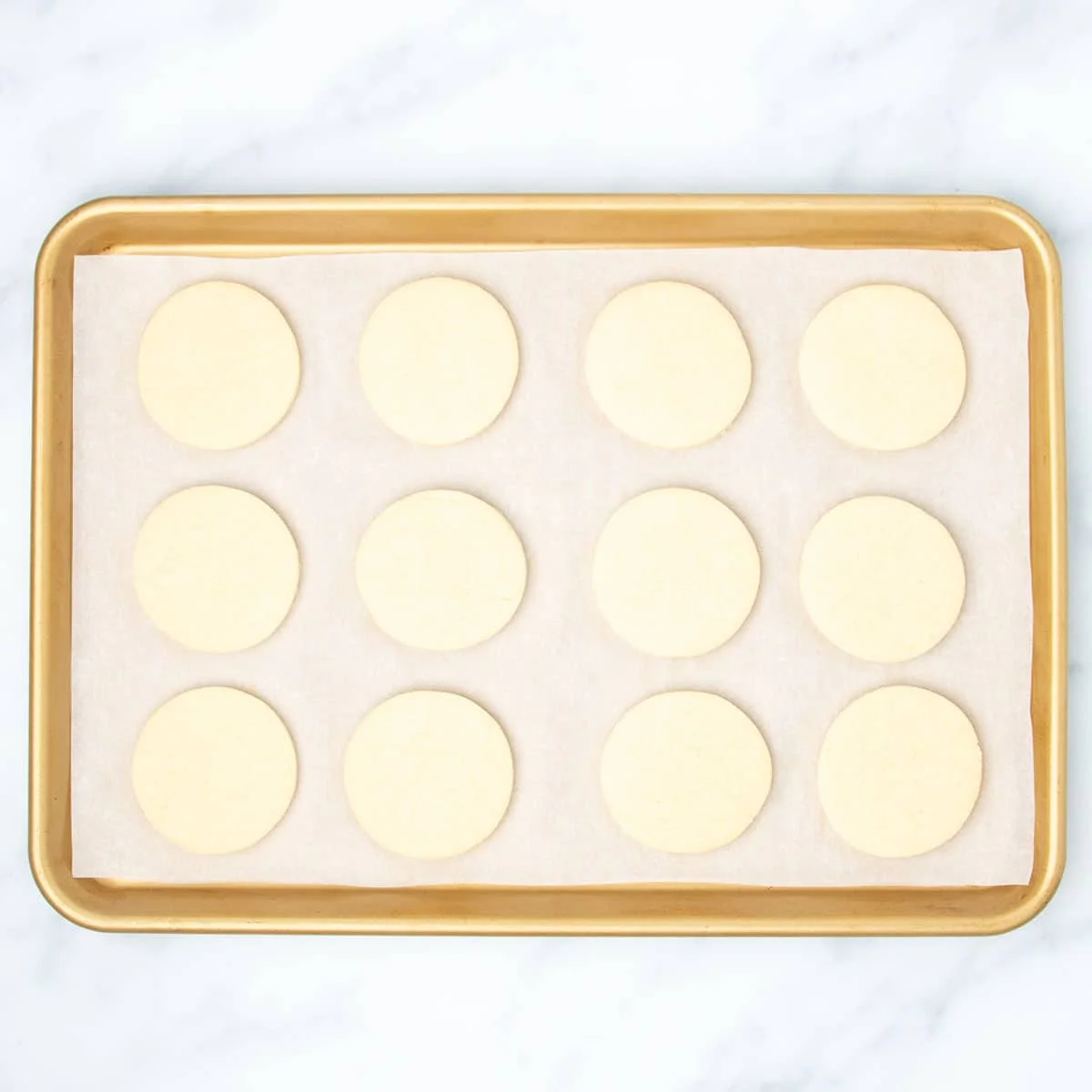 Same baking sheet with 12 baked cookie rounds.
