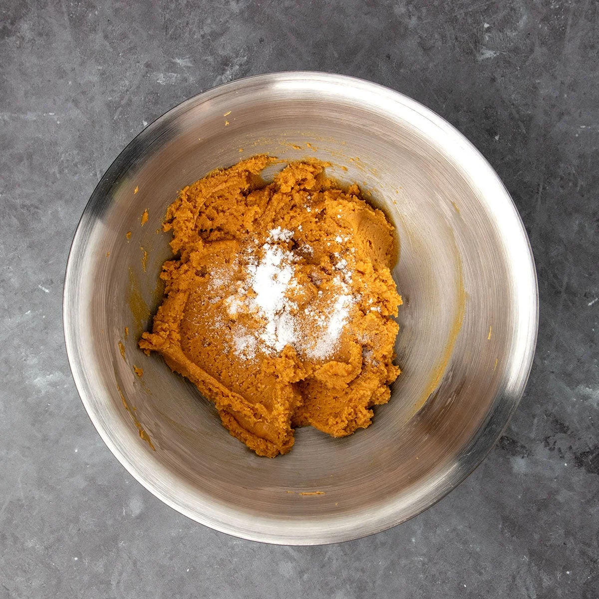 Same bowl with thick brown cookie dough with white powder on top