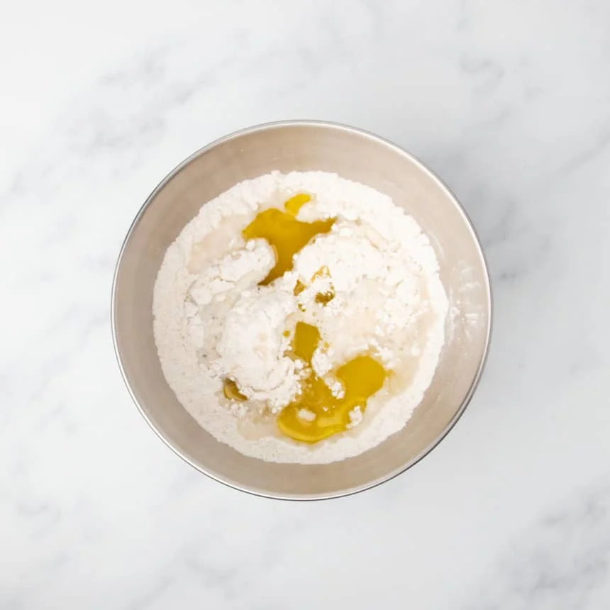 same bowl with yellow olive oil added on top of water over flour