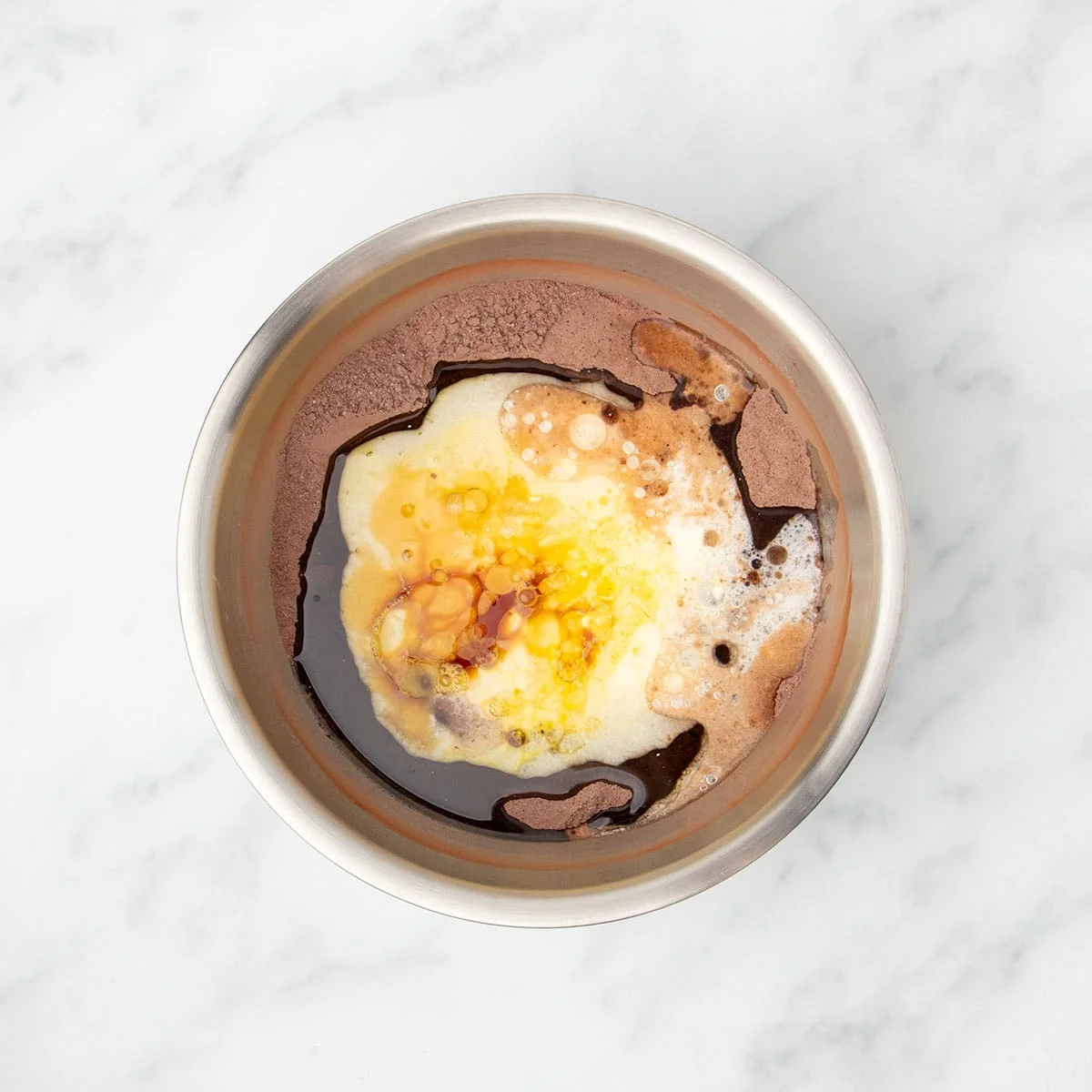 same bowl, with yellow, white and brown wet ingredients sitting on top of brown powder