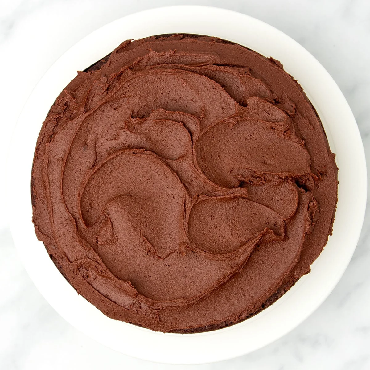 same brown cake with same frosting spread on top of cake with swirls