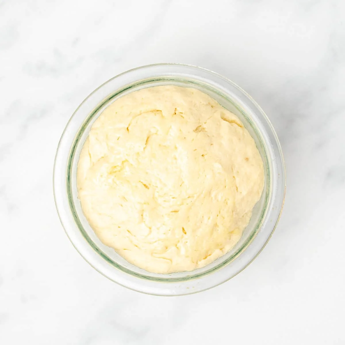 same light yellow dough in pyrex bowl now risen to about 50 percent larger in volume than before