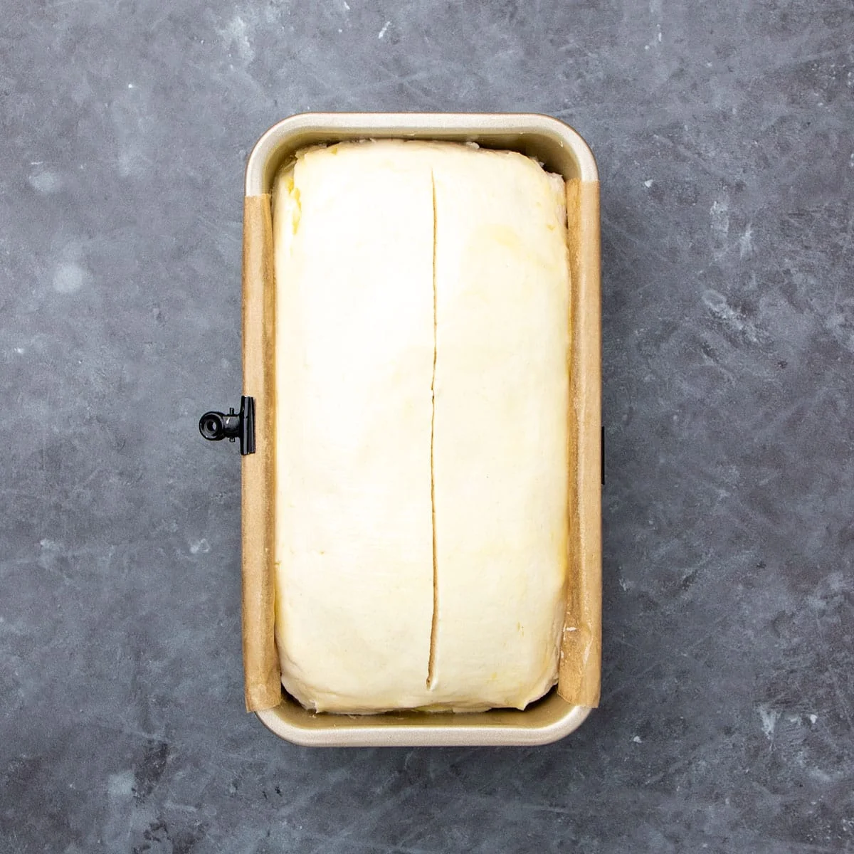 Same loaf pan with raw dough, now risen in pan and a horizontal slice down the center.
