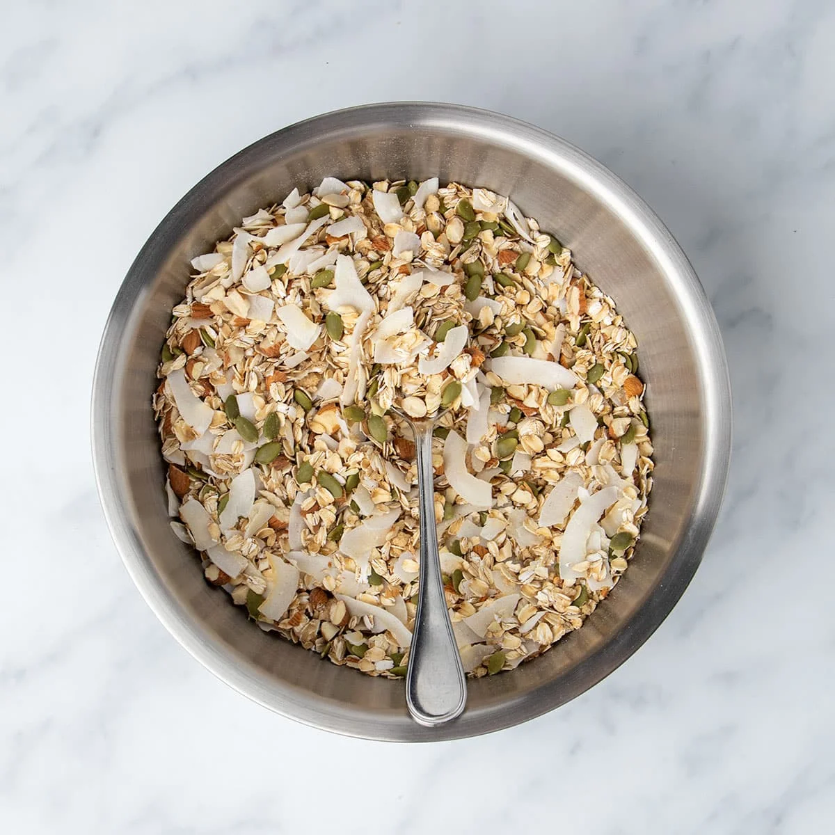 same mixing bowl with those same ingredients mixed with large metal mixing spoon