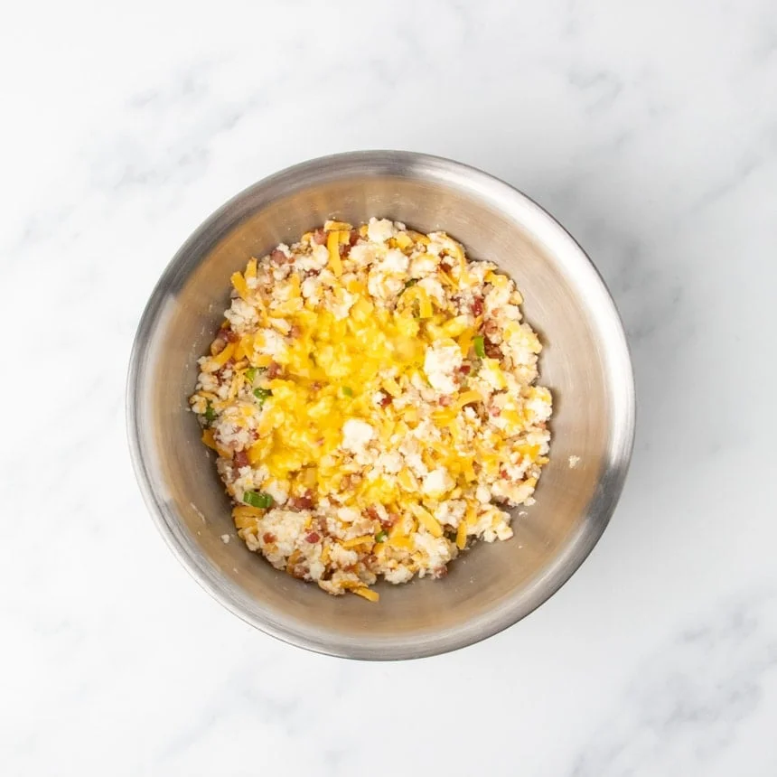 Same mixture with one beaten egg visible on top in a stainless steel bowl.