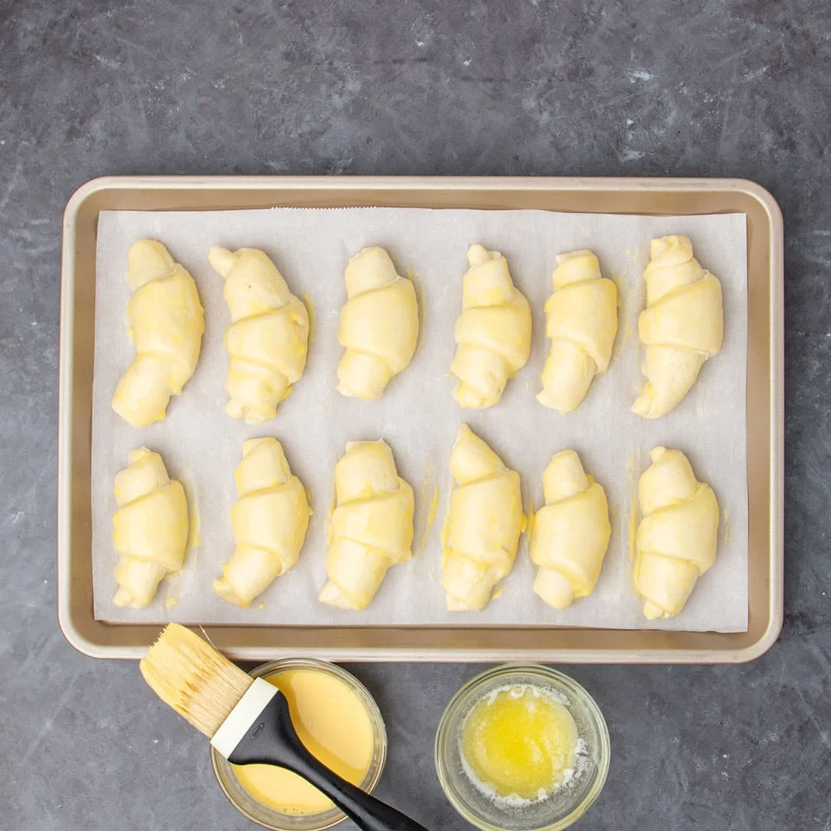 same raw crescent rolls brushed with yellow egg wash and melted butter