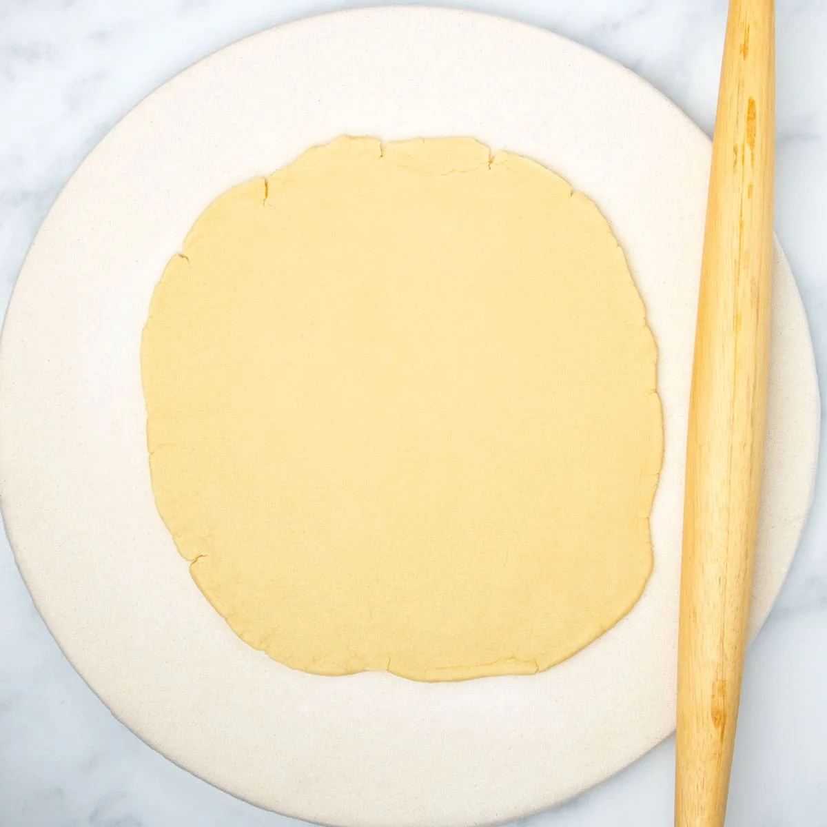 Same raw dough rolled into 1/3-inch round with blond wood French rolling pin.