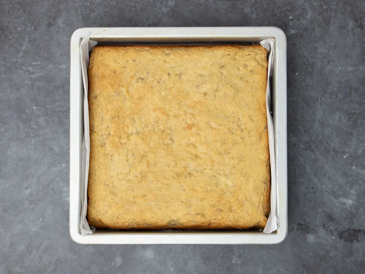 same square metal pan with light yellow cake baked