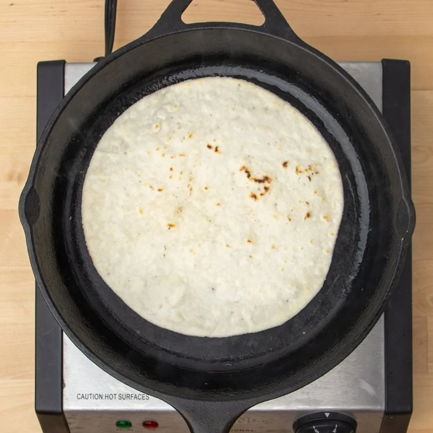 same tortilla flipped in skillet with some golden brown spots now on top