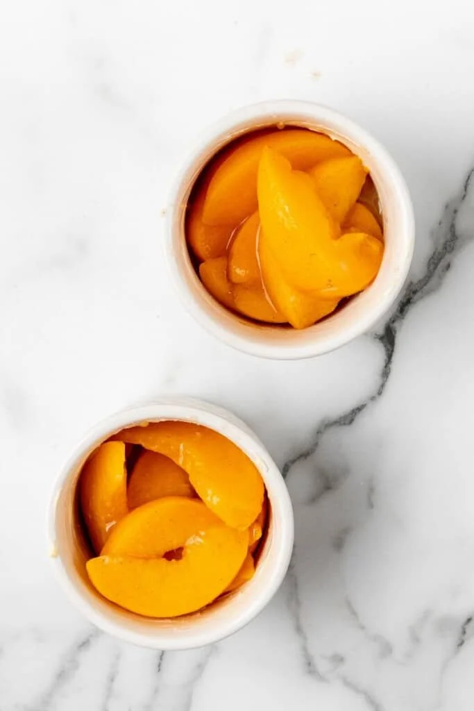 Seasoned peaches divided into ramekins.