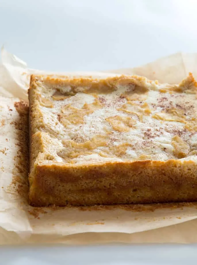 Side view of apple custard cake on brown parchment paper