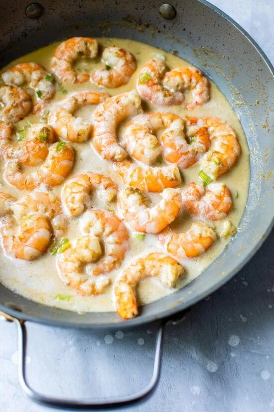 Skillet with shrimp, coconut milk and green curry paste.
