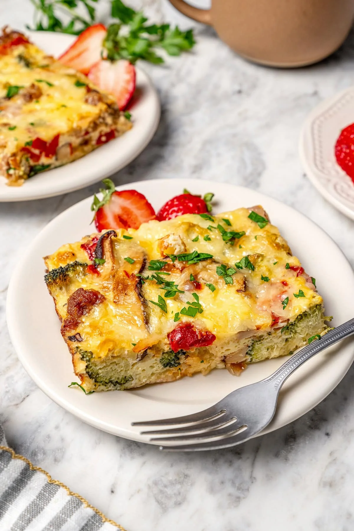 Slice of breakfast casserole on plate with fork.