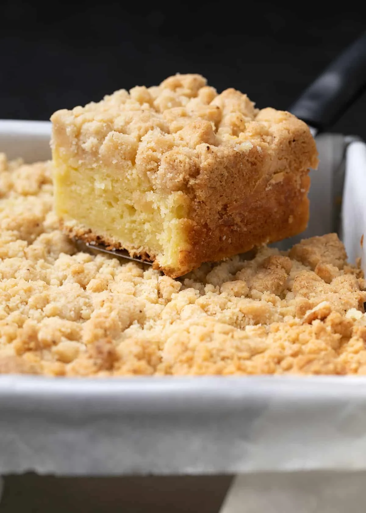 slice of gluten free coffee cake on spatula on top of cake in pan