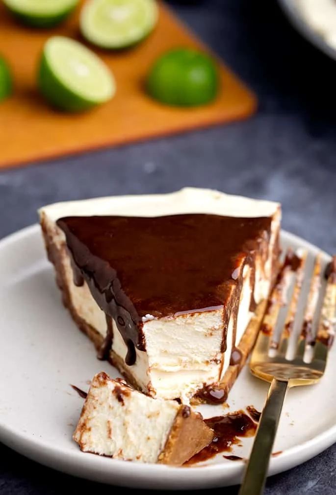 Slice of pie with chocolate topping with fork on white plate with tip of pie cut off