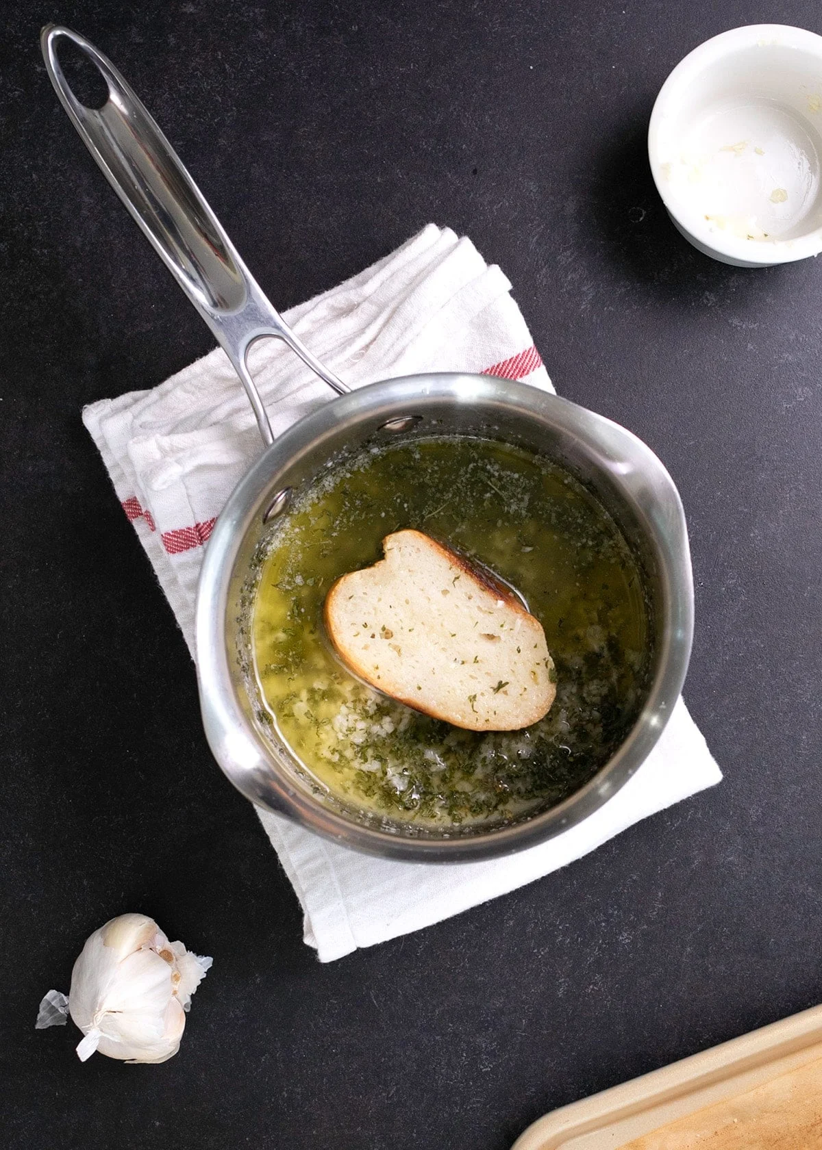Sliced French bread being dipped in garlic butter