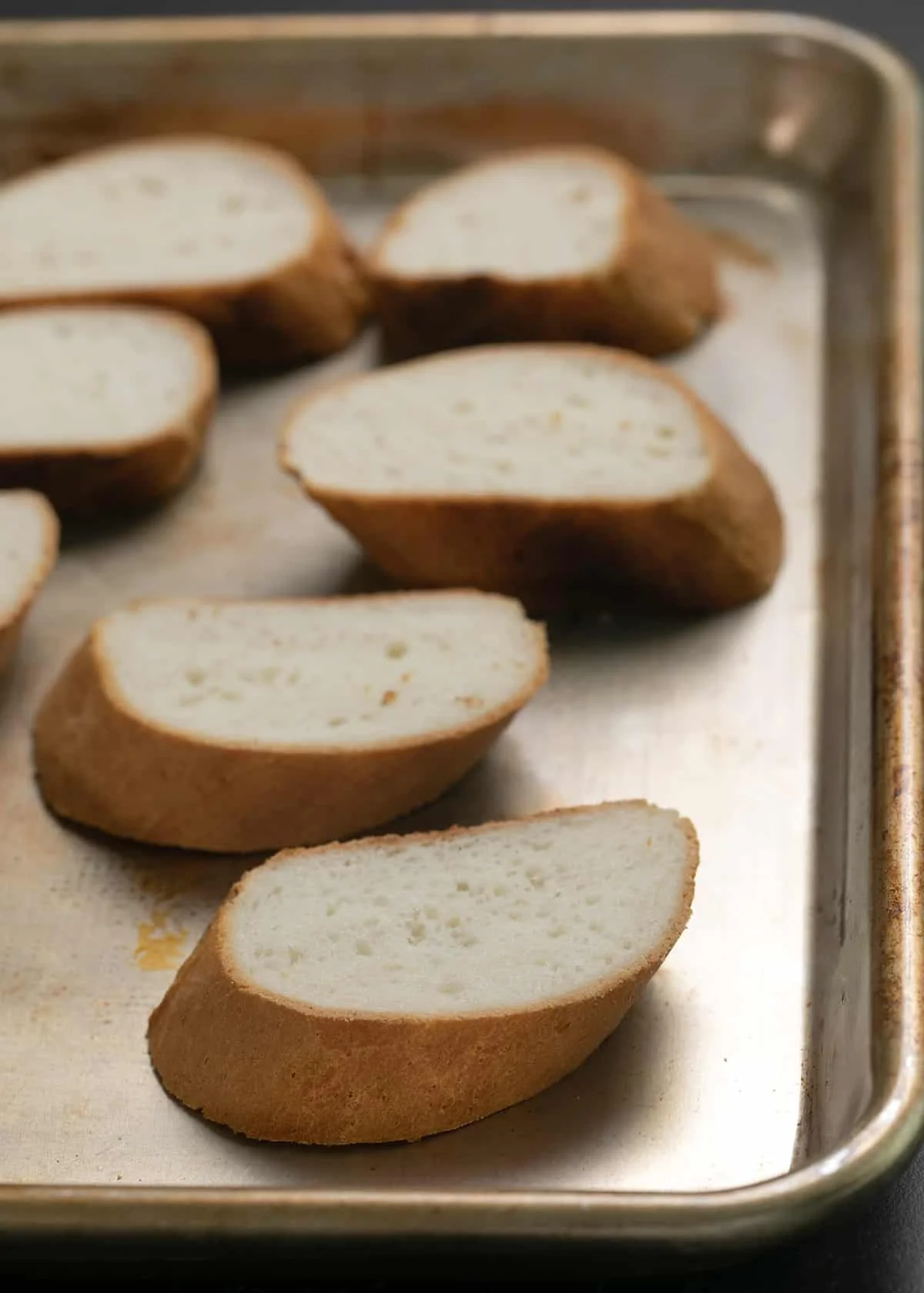Sliced pieces of French bread on a baking sheet