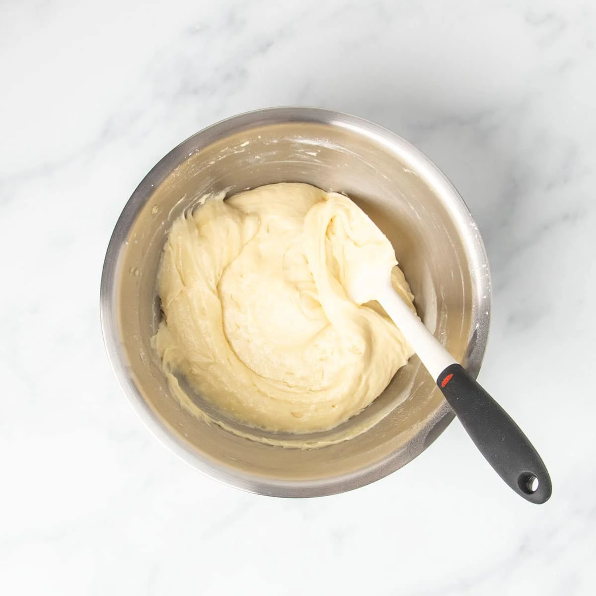soft, thick light yellow gluten free vanilla cupcake batter with swirl from being mixed with white spatula with black handle