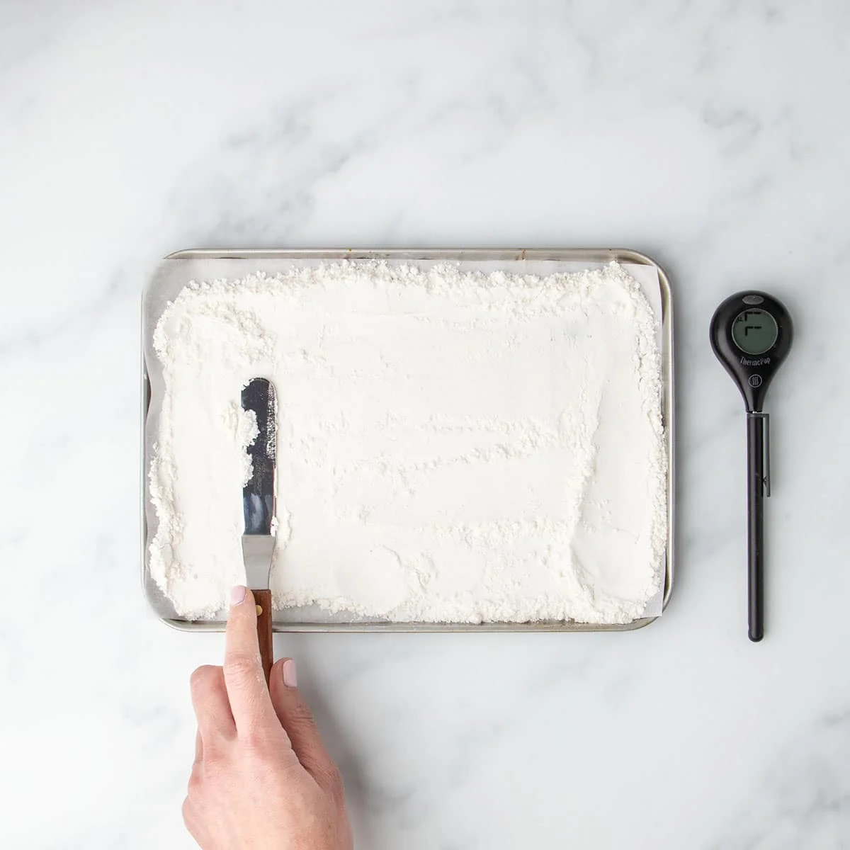 Spreading flour on a baking sheet for heat treatment.