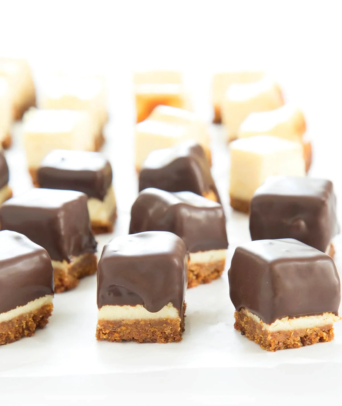Squares of cheesecake half with chocolate coating and half without