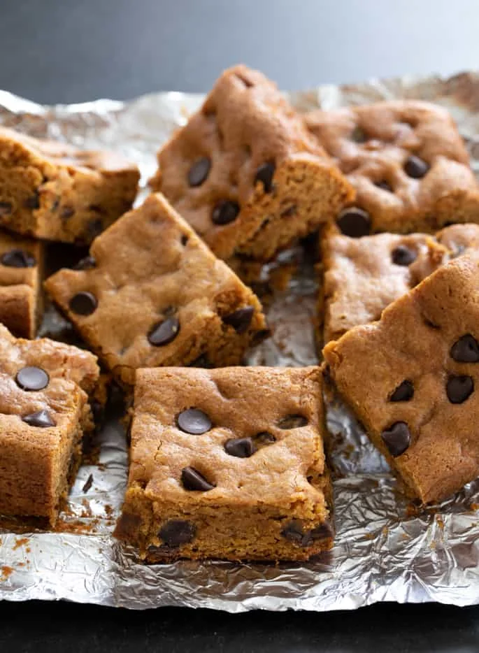 Squares of gluten free pumpkin chocolate chip in a pile on foil.