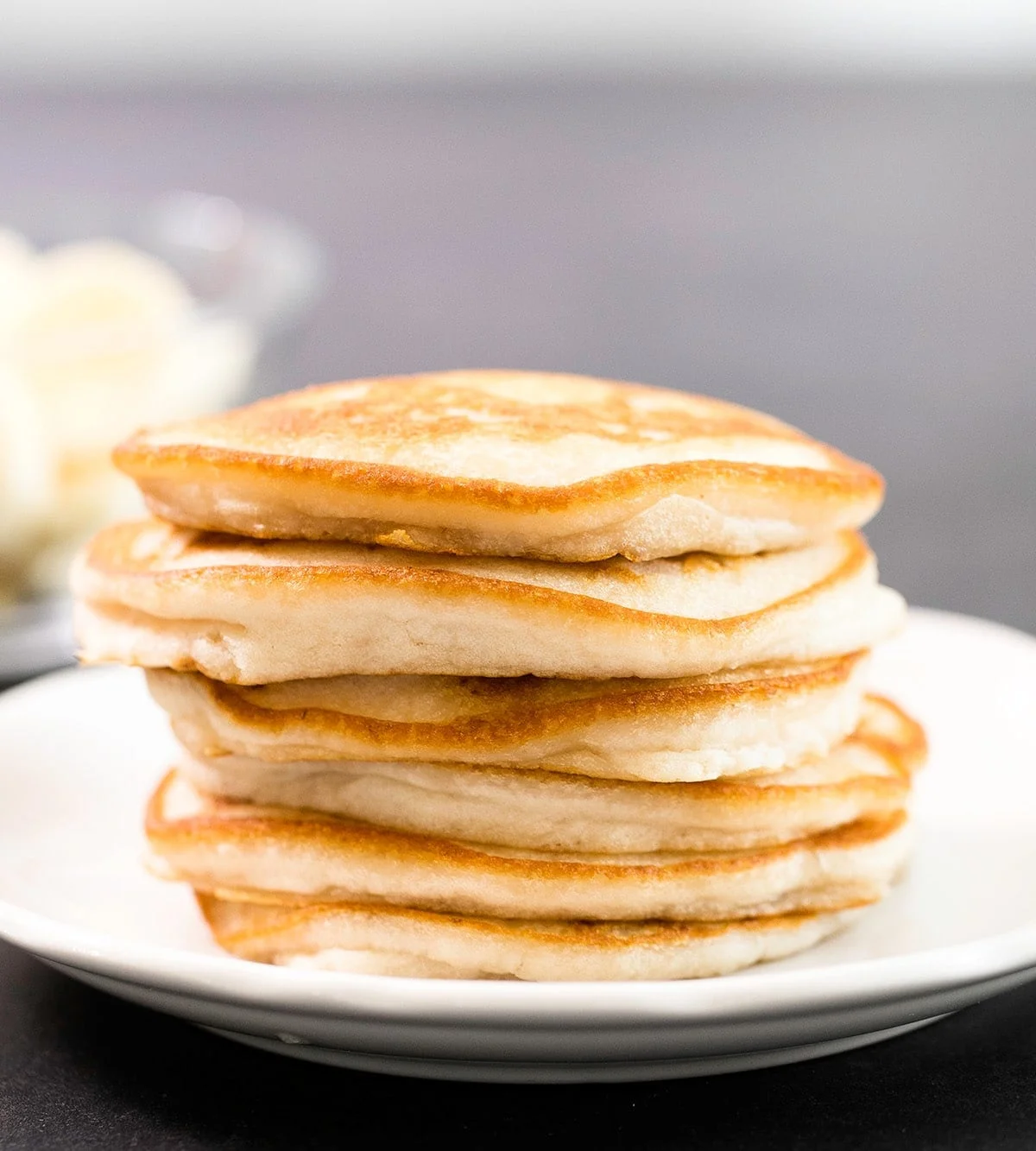 stack of 6 plain round pancakes on a small white plate