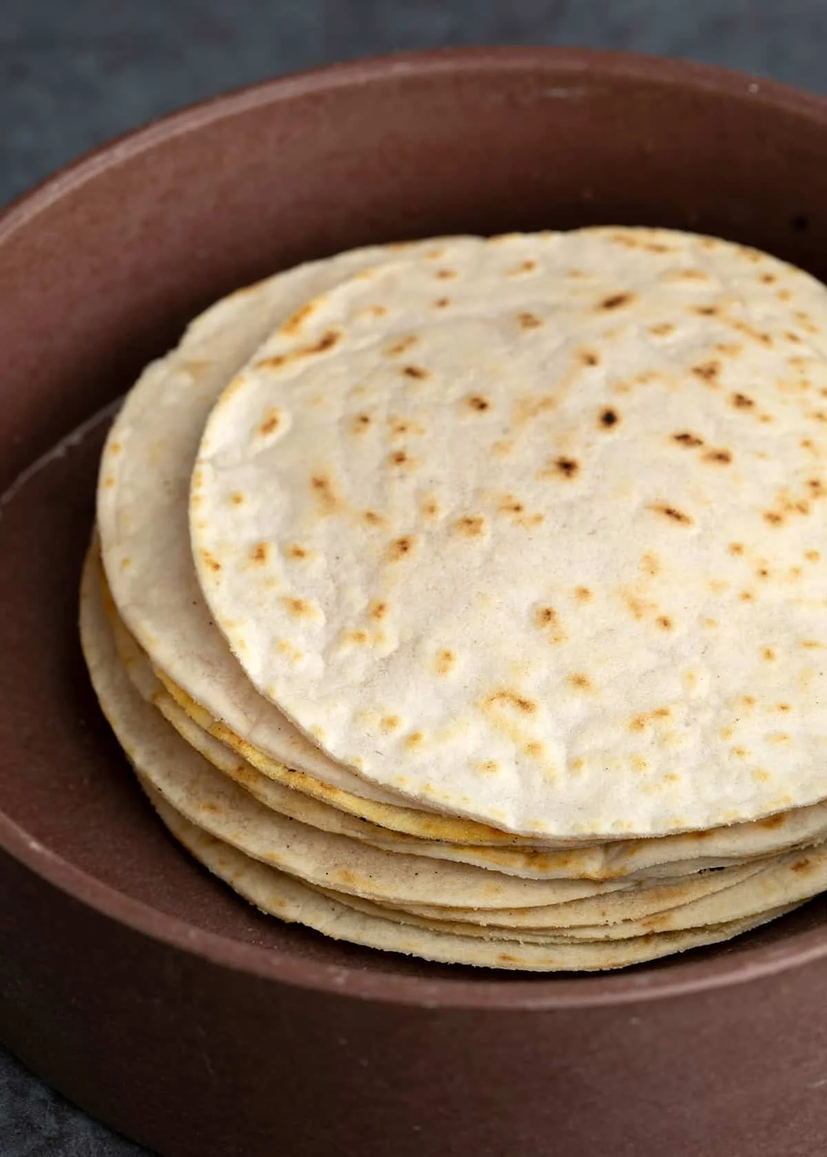 Stack of cassava flour tortillas in round brown tortilla holder